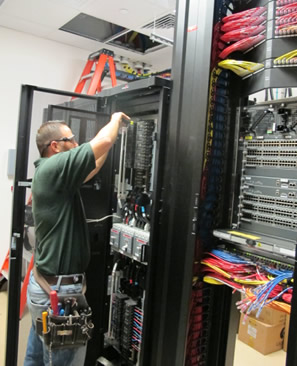 A technician connecting data wires to ports within a networking panel.